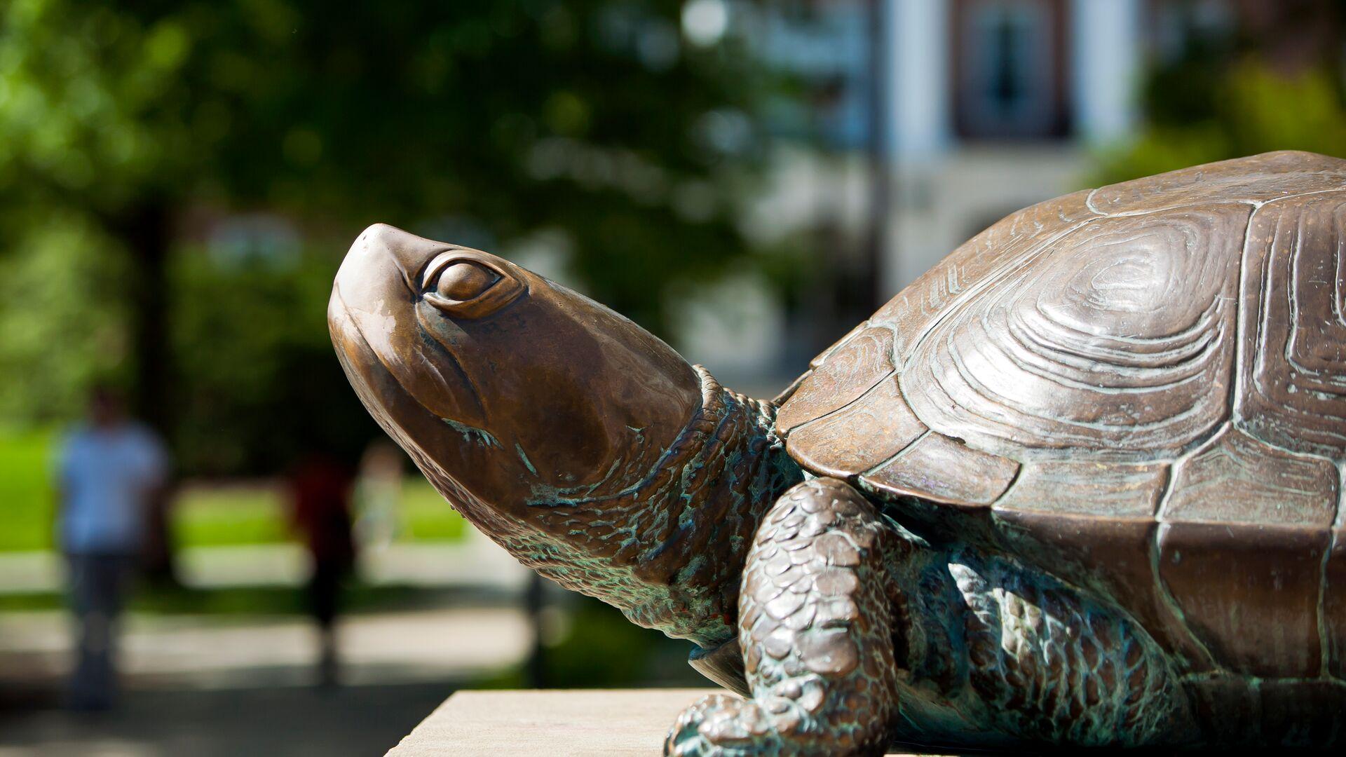 View of Testudo bronze statue in front of McKeldin Library, with students walking in the background. 